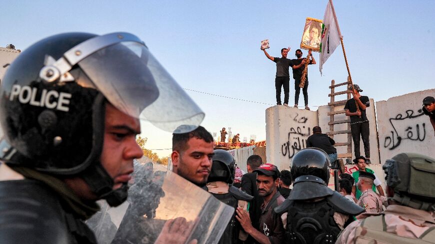 Iraqi riot police try to disperse protesters who breached the Swedish embassy compound and set fires inside