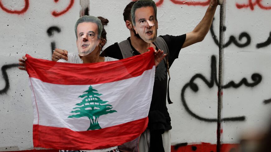 Lebanese anti-government protesters hold a mask of Lebanon's Central Bank Governor Riad Salameh during a protest in front of the central bank headquarters in Beirut to protest against the economic policies of the bank on November 27, 2019. - Since September, debt-saddled Lebanon has had a liquidity crisis, with banks rationing the supply of dollars. As a result, the dollar exchange rate on the parallel market has topped 2,000 Lebanese pounds -- a spike from the pegged rate of 1,507. (Photo by JOSEPH EID / A
