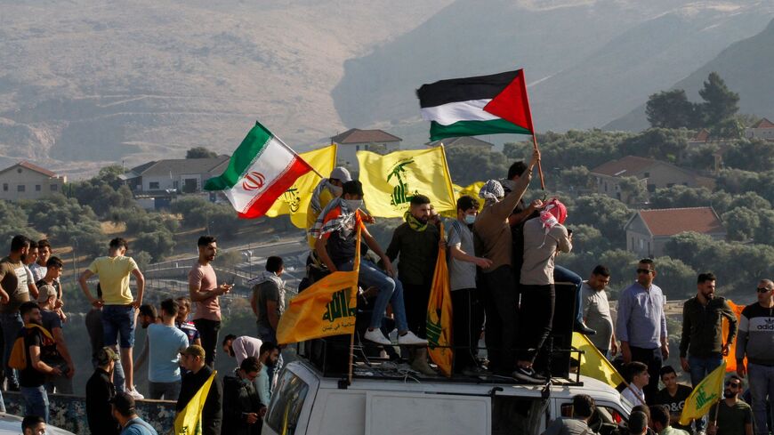 Supporters of Lebanon's Hezbollah lift its flags (C) alongside those of Iran (L) and Palestine, during an anti-Israel protest in the southern Khiam area by the border with Israel, facing the northern Israeli town of Metula, on May 14, 2021.