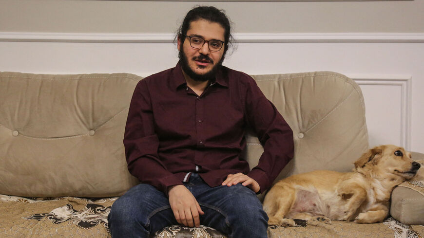 Egyptian researcher Patrick Zaki is pictured next to a dog at his family home in Cairo, on Dec. 9, 2021.