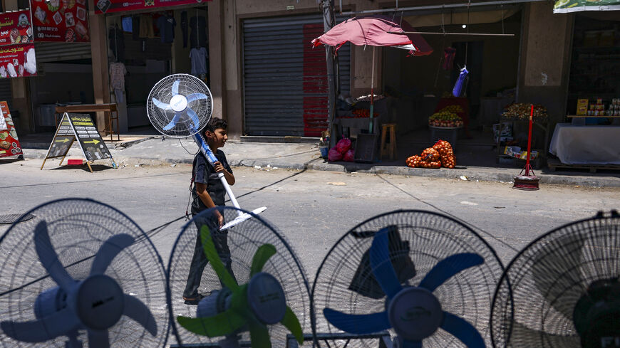 A young boy carries home a battery-powered fan amid a heatwave and electricity shortage in Gaza City, Gaza Strip, July 19, 2023.